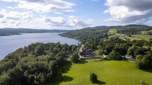 An aerial view of Wray Castle, with Wray Castle House on the right and Lake Windermere on the left, Cumbria